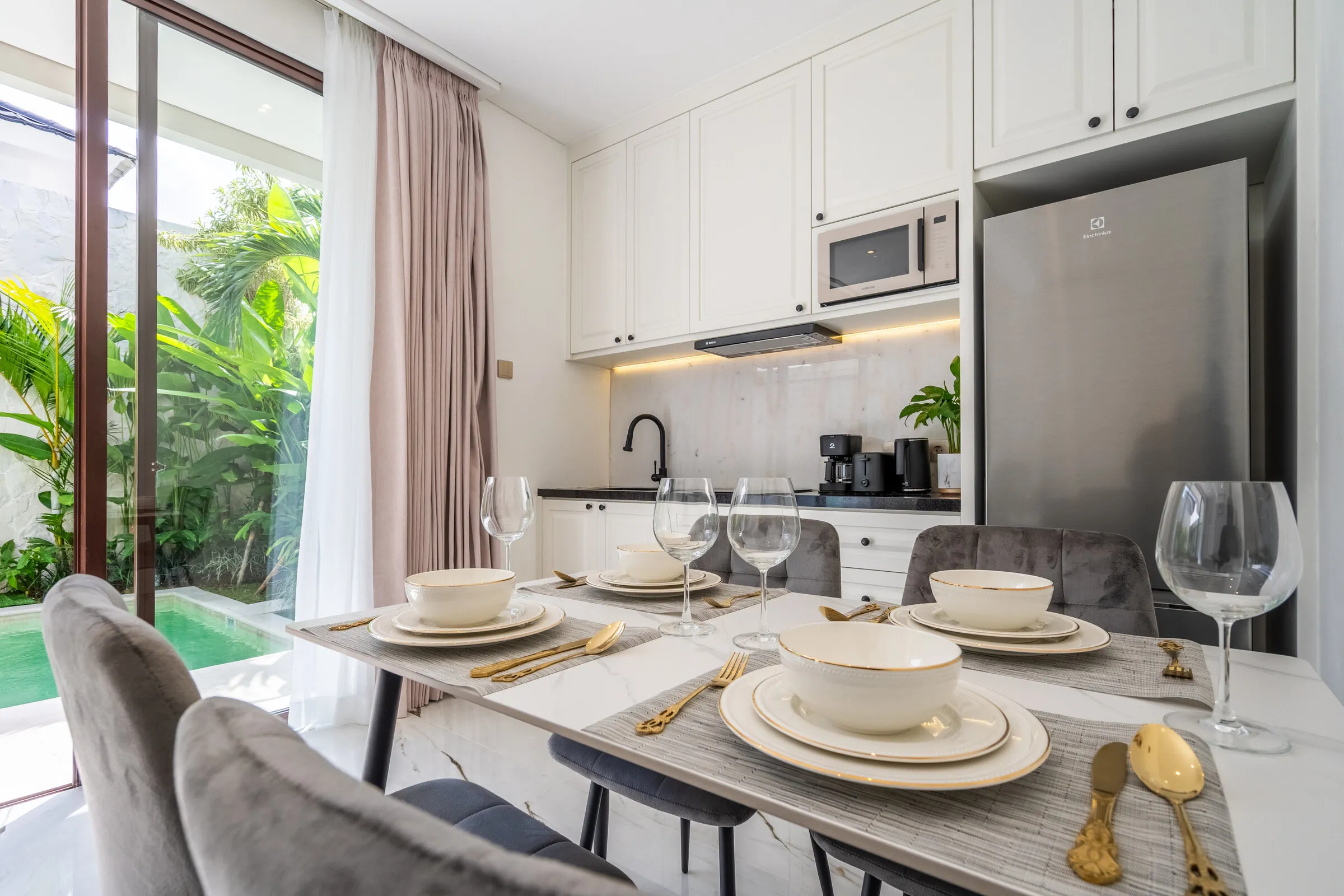Dining table set for four beside the kitchen and pool