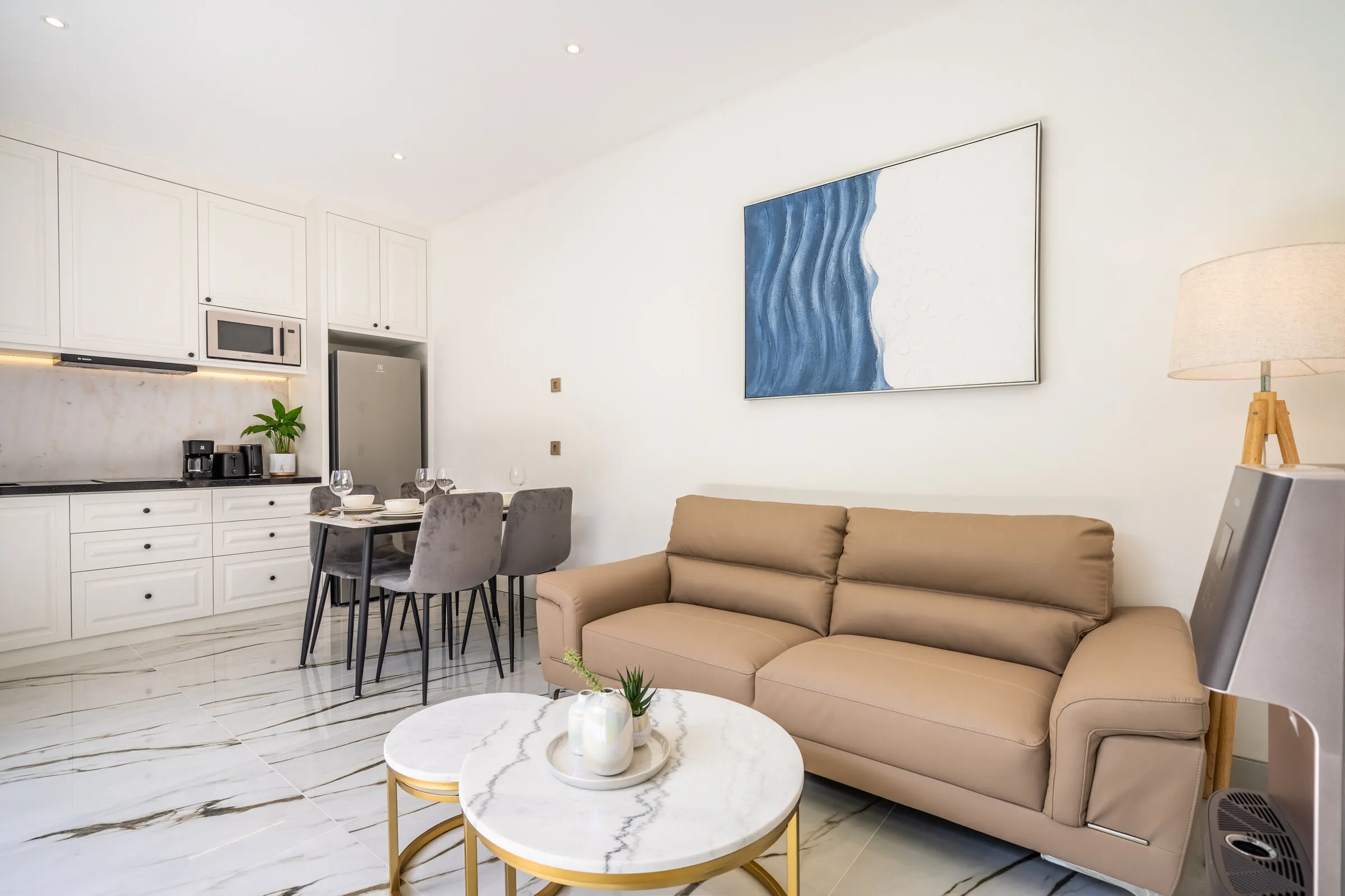 Living room with leather sofa, marble side tables and blue artwork