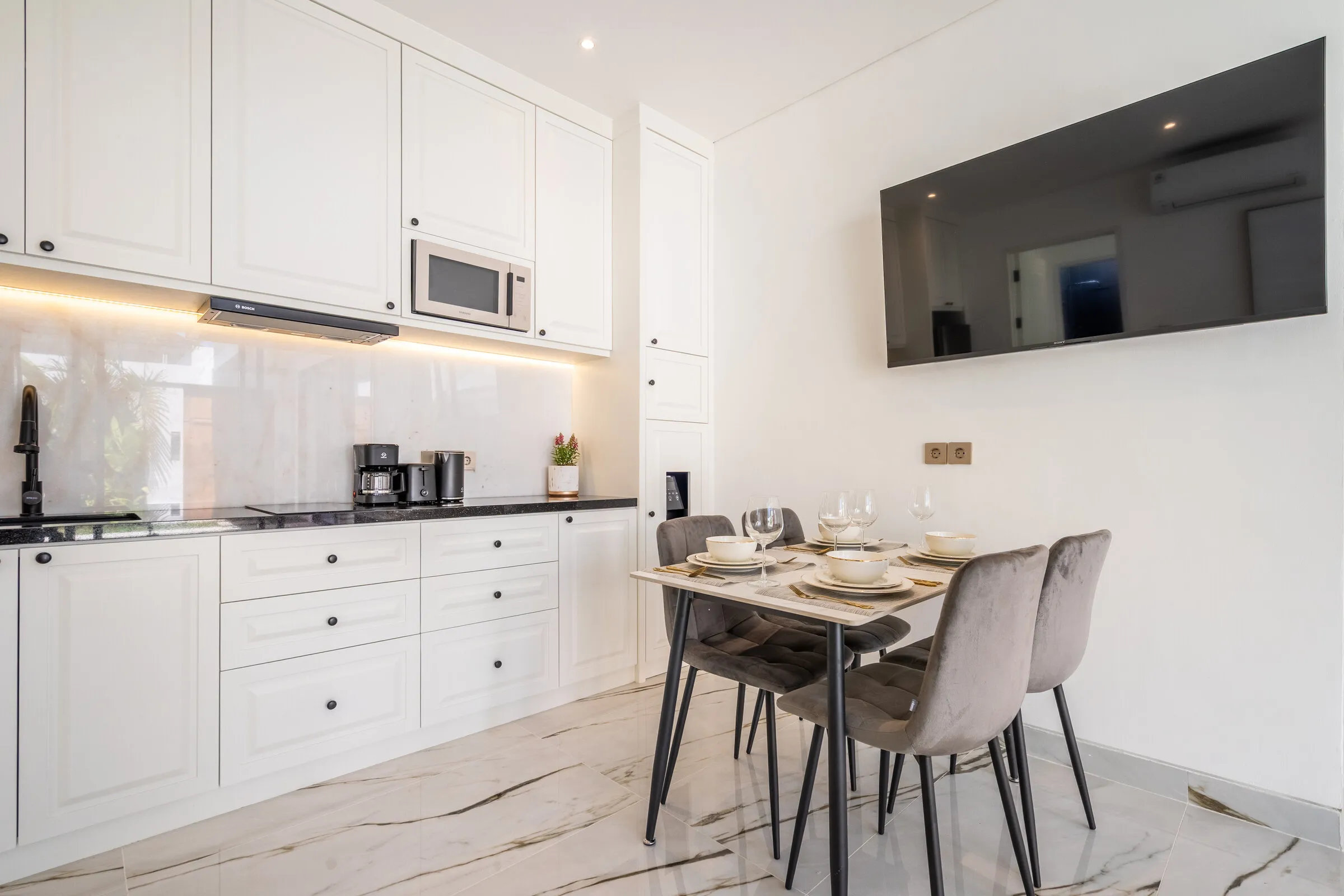 White kitchen with marble splashback and dining table