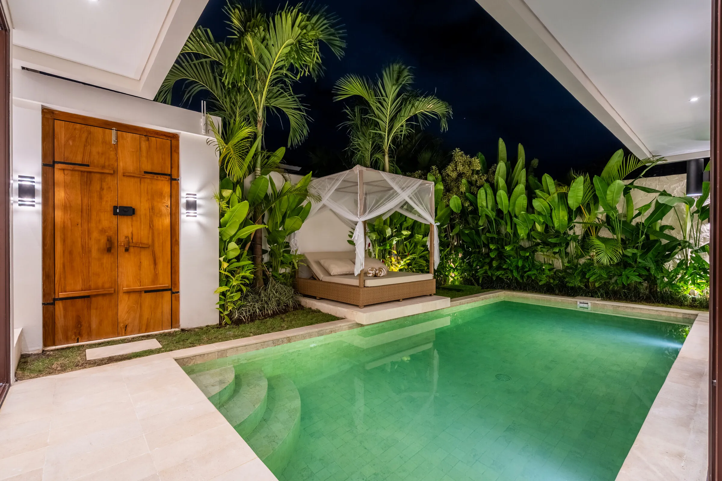 The pool and garden of a two-bedroom villa lit at night
