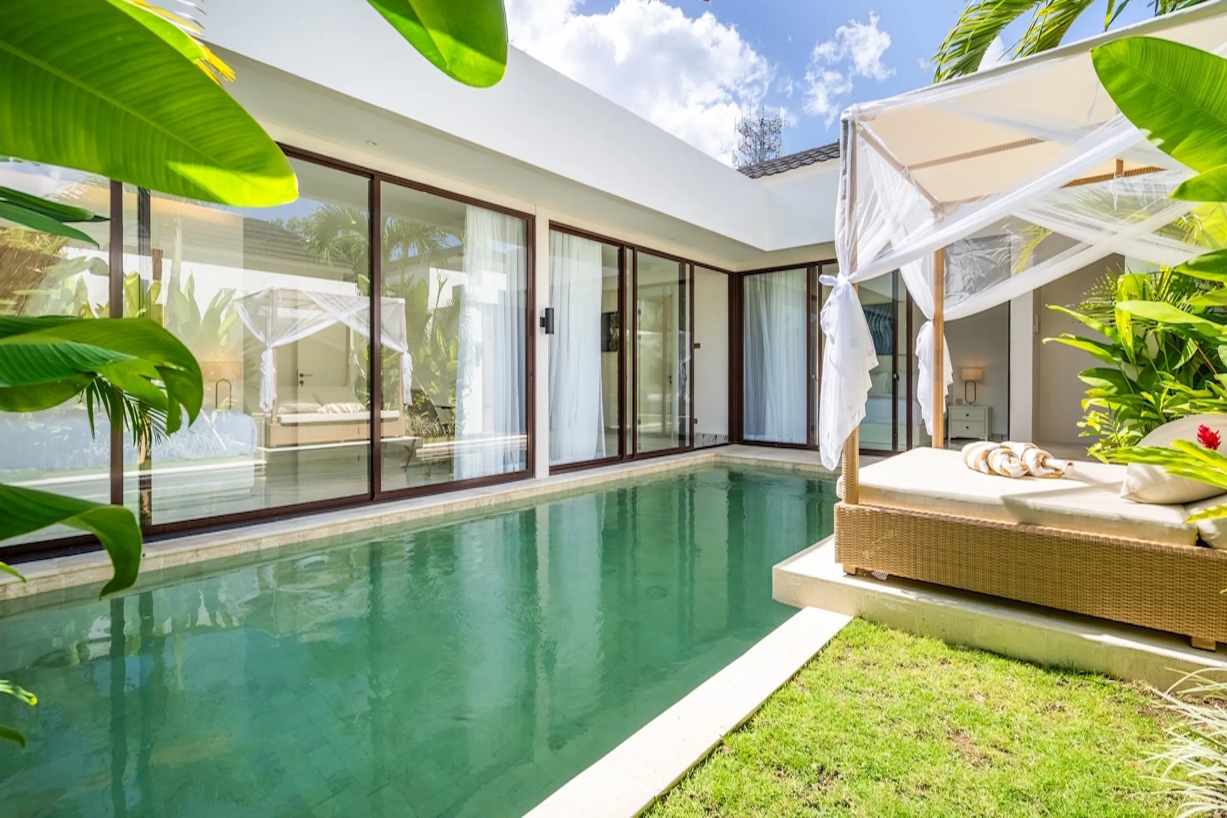 Canopied daybed at the end of the pool among palms